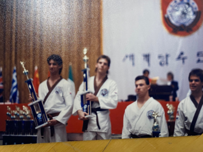 Dr. Salvatore Sandone celebrates winning the 1988 World Tang Soo Do Championships as an adult brown belt, holding a trophy alongside fellow competitors.